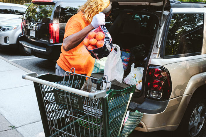 A woman loads her car at a food pantry in Norfolk, Virginia. Inflation sent food prices soaring just as emergency pandemic support for many people ended.