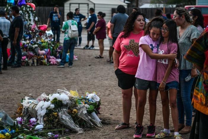 People mourn Tuesday at a makeshift memorial for the victims of the Robb Elementary School shooting in Uvalde, Texas. The Texas town of Uvalde began on Tuesday laying to rest the 19 young children killed in an elementary school shooting that left the small, tight-knit community united in grief and anger.