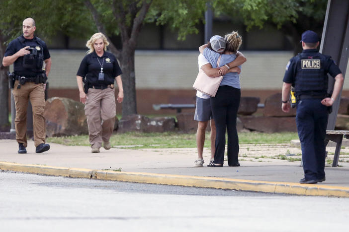 Two people hug outside at Memorial High School where people were evacuated from the scene of a shooting at the Natalie Medical Building on Wednesday, in Tulsa, Okla.
