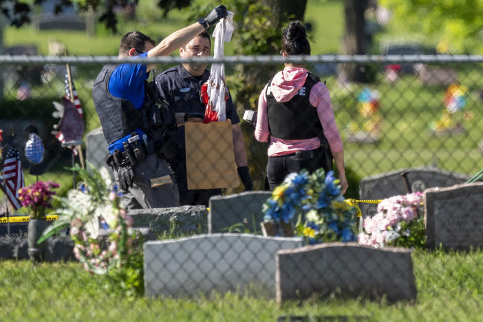 Law enforcement examine a bloody garment while working at the scene of a shooting on Thursday at Graceland Cemetery in Racine, Wis.