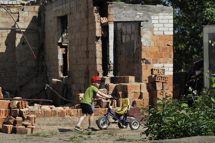 A boy plays in front of a destroyed house in the village of Andriivka, Kyiv region, on Friday, the 100th day of the Russian invasion of Ukraine.
