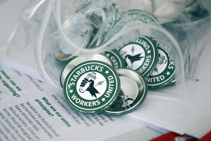 Pro-union pins sit on a table during a watch party for Starbucks' employees union election in December in Buffalo, N.Y. Starbucks union organizers say the company is closing a New York store to retaliate.