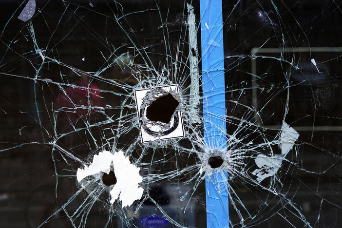 A storefront window with bullet holes is seen at the scene of a fatal shooting on South Street in Philadelphia on Sunday morning.