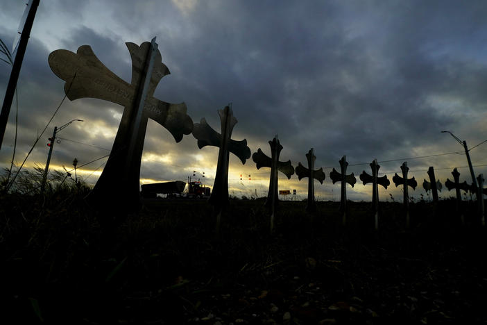 A truck passes crosses placed along the highway to honor the victims killed in the recent school shooting at Robb Elementary School.