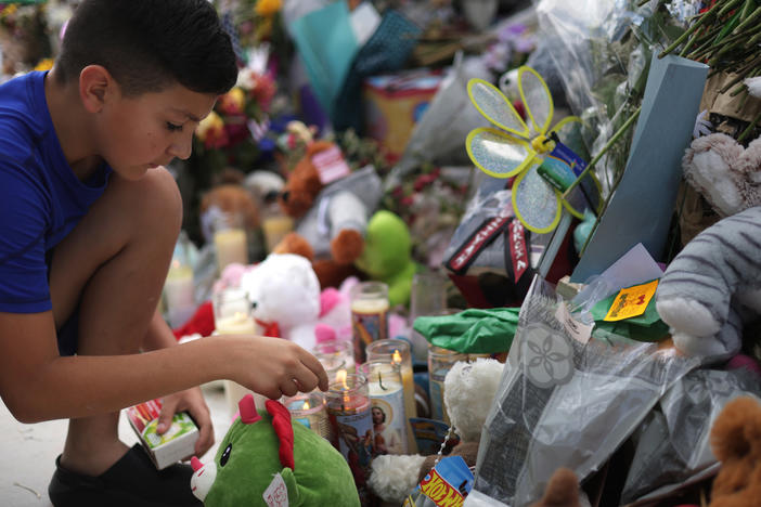A child lights candles at a memorial for the victims of a May 24 mass shooting at Robb Elementary School in Uvalde, Texas, that killed 21 people, mostly children.
