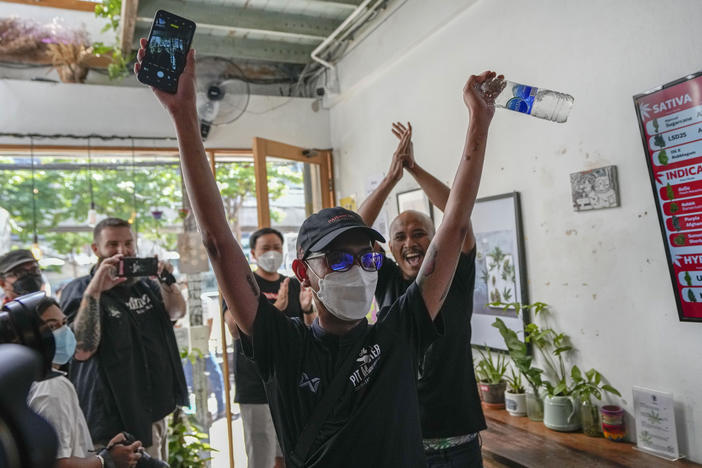 The first customer of the day, Rittipomng Bachkul celebrates after buying legal marijuana at the Highland Cafe in Bangkok, Thailand, Thursday, June 9, 2022.