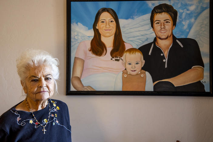 Donna Casasanta poses in front of a painting showing her late son, Harold Dean Clouse Jr., with Clouse's wife, Tina Gail Linn, and their daughter, Holly Marie Clouse, at Casasanta's Edgewater, Fla., home on Friday, Jan. 14, 2022.