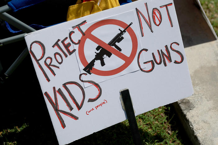 A sign reading "Protect Kids Not Guns" sits on a chair at a vigil for victims of recent mass shootings in Sunrise, Fla. The vigil was held by Moms Demand Action, to mourn victims of the mass shootings in Buffalo, N.Y., and Uvalde, Texas.