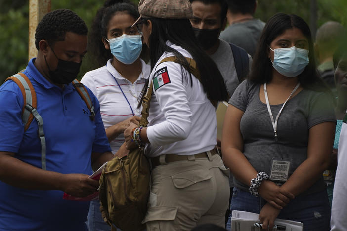 Migrants gathered at the Border Transit Comprehensive Care Center are given documents by an official, center, that allow them to legally travel through Mexico.