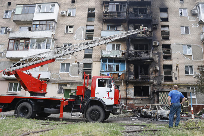 Firefighters work to extinguish an apartment building and cars burning after shelling in Donetsk, eastern Ukraine, on Monday.