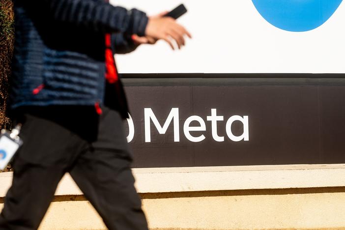 A person walks past a sign bearing Meta's logo at the company's Menlo Park headquarters in October 2021. The company is introducing new safety measures for younger Instagram users after facing widespread scrutiny.