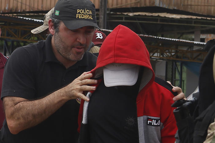 A police officer escorts a suspect in the area where Indigenous expert Bruno Pereira and freelance British journalist Dom Phillips disappeared, in Amazonas state, Brazil, June 15, 2022.