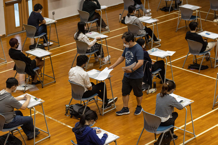 An invigilator distributes papers to students taking the Hong Kong Diploma of Secondary Education exams on April 22, 2022 in Hong Kong.