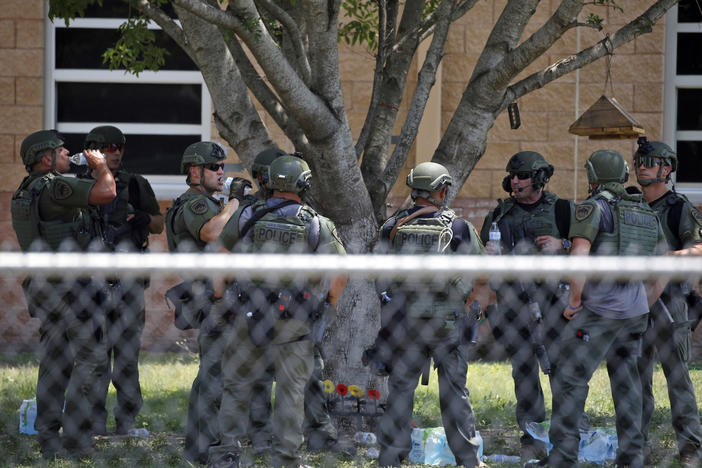 Law enforcement personnel stand outside Robb Elementary School following a shooting on May 24 in Uvalde, Texas. When the gunman arrived at the school, he hopped its fence and easily entered through an unlocked back door, police said.