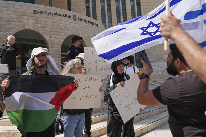 Supporters of Mohammed el-Halabi hold a Palestinian flag and placards as protesters wave Israeli flags, outside the district court in the southern Israeli city of Beersheba, Wednesday, June 15, 2022.