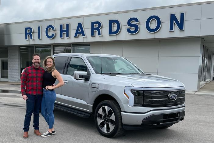 Nick Schmidt poses with his wife after picking up his brand new electric F-150. Schmidt was the first buyer to get the F-150 Lightning as auto makers are betting billions in an electric future.