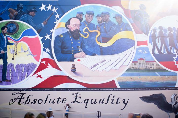 People take pictures next to a mural during a Juneteenth celebration in Galveston, Texas, on June 19, 2021. Last year, the U.S. designated Juneteenth a federal holiday with President Joe Biden urging Americans "to learn from our history."
