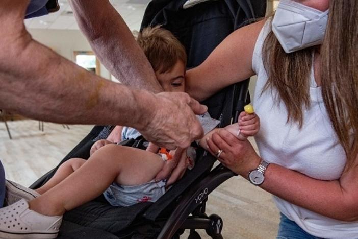 A mother holds her 1-year-old son as he receives the child Covid-19 vaccine in his thigh at Temple Beth Shalom in Needham, Mass., on June 21, 2022. The temple was one of the first sites in the state to offer vaccinations to anyone in the public.