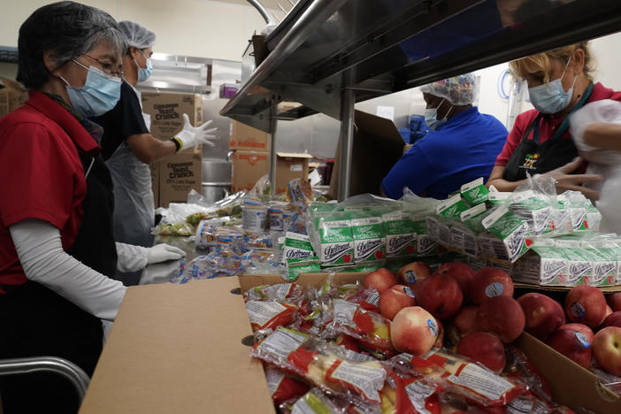 Los Angeles Unified School District food service workers  pre-package hundreds of free school lunches in plastic bags.