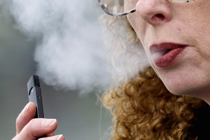 A woman exhales while vaping from a Juul pen e-cigarette in 2019. A federal court has temporarily put on hold an FDA ban against the company's vaping products.