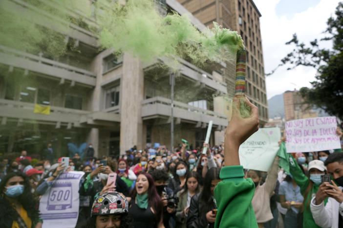 An abortion-rights activist holds up a flare outside the Constitutional Court in Bogotá, Colombia, in February. The court later ruled that people can get abortions until the 24th week of pregnancy without any permits from lawyers or doctors.