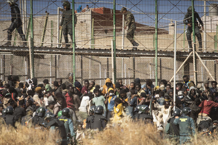 Riot police officers cordon off the area after migrants arrive on Spanish soil and crossing the fences separating the Spanish enclave of Melilla from Morocco in Melilla, Spain, Friday, June 24, 2022.