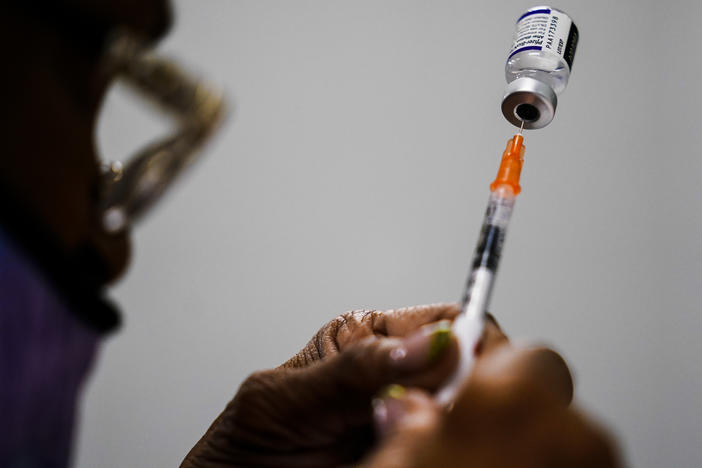 A syringe is prepared with the Pfizer COVID-19 vaccine at a vaccination clinic in Chester, Pa., on Dec. 15, 2021. Pfizer says tweaking its COVID-19 vaccine to better target the omicron variant is safe and boosts protection.