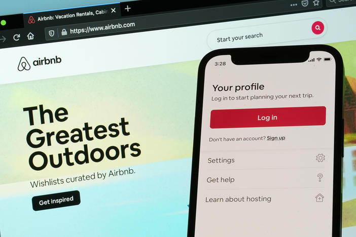 The login page for Airbnb's iPhone app is seen in front of a computer displaying Airbnb's website, Saturday, May 8, 2021, in Washington.