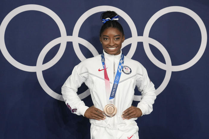 Simone Biles poses wearing her bronze medal from balance beam competition during artistic gymnastics at the Summer Olympics on Aug. 3, 2021, in Tokyo. President Biden will present the Presidential Medal of Freedom to Biles and 16 others at the White House next week.