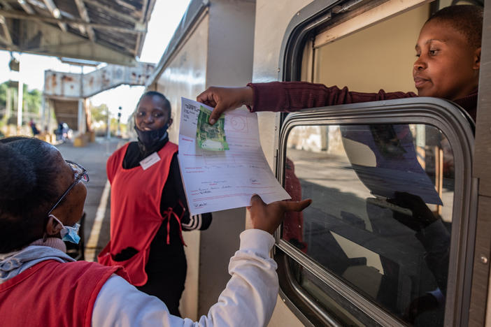 A pharmacist on the Phelophepa health-care train takes payment for a patient's prescription.