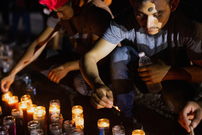People gather at a makeshift memorial for the 53 migrants who died this week in San Antonio.