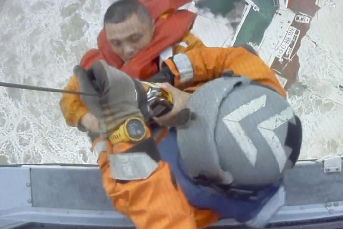 Helicopter crew members winch up a man from a sinking ship in the South China Sea on Saturday as a storm was moving in the area.