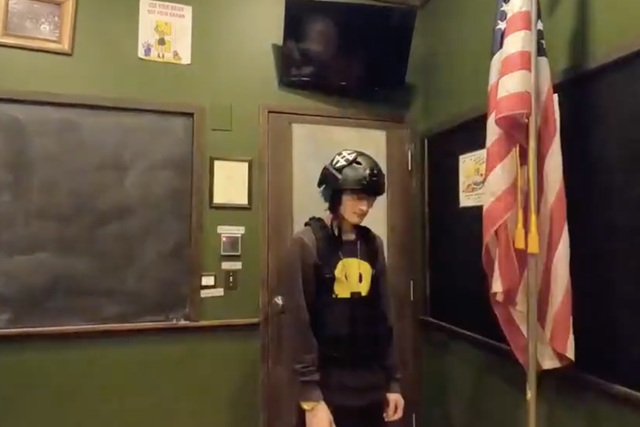 Crimo made rap music under the name Awake The Rapper. In one video, he wears a helmet and vest inside an empty classroom and scatters bullets across the floor.