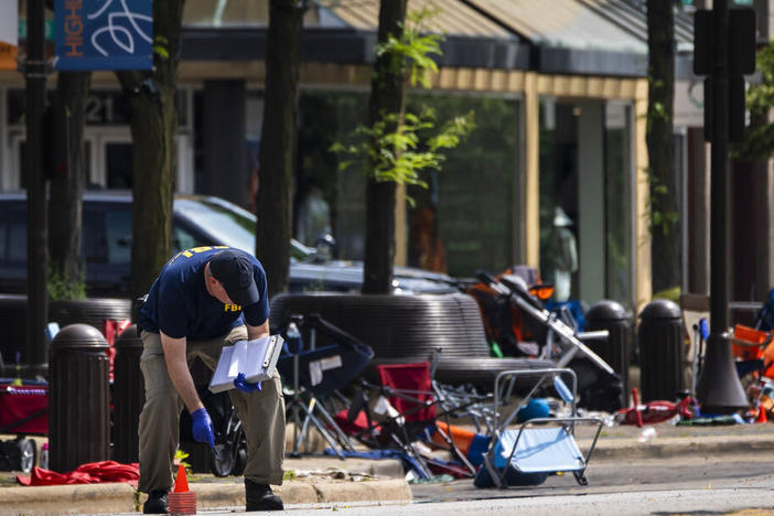 Members of the FBI's Evidence Response Team Unit investigate Tuesday in downtown Highland Park, Ill., the day after a deadly mass shooting. Police say the gunman who attacked an Independence Day parade in suburban Chicago fired more than 70 rounds with an AR-15-style gun.