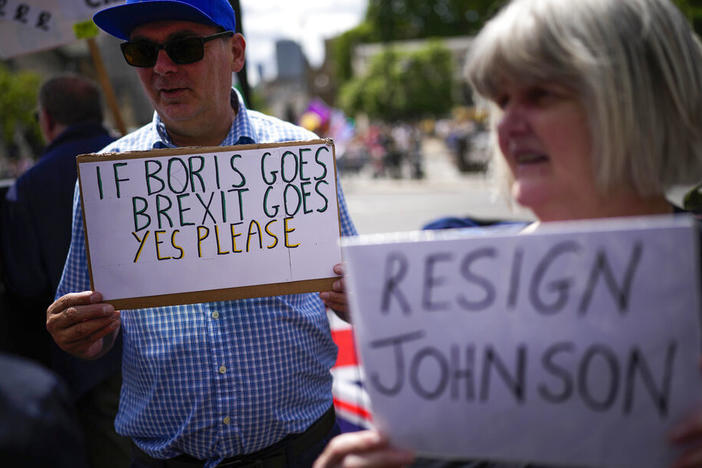 People holds signs as they protest Wednesday outside the Houses of Parliament in London.