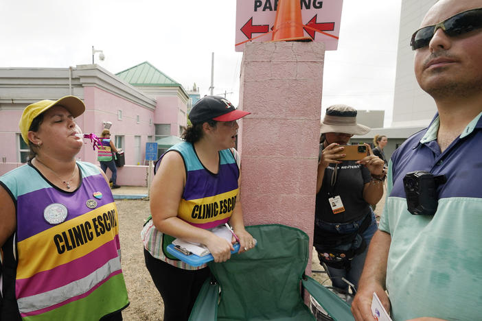 Clinic escorts use party horns and whistles to counter the presence of anti-abortion activist Gabriel Olivier, right, outside the Jackson Women's Health Organization clinic in Jackson, Miss., on July 6, 2022.