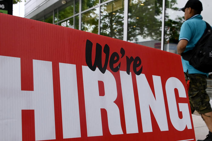Fewer jobs were added in June, but the labor market is still tight. A man walks past a "now hiring" sign posted outside of a restaurant in Arlington, Va., last month.