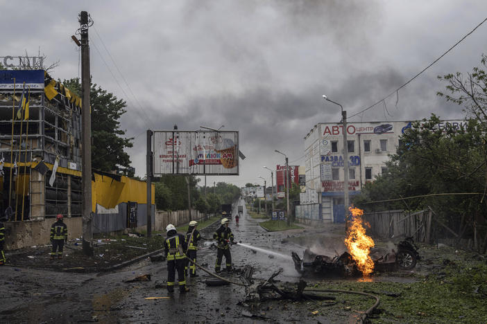 Rescue workers put out the fire of a destroyed car after a Russian attack in a residential neighborhood in downtown Kharkiv, Ukraine, on Monday.
