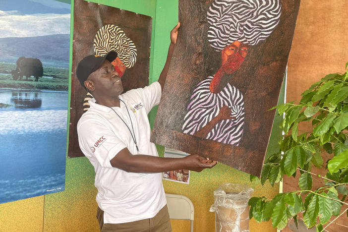 Fred Mutebi, a Ugandan artist, holds up one of his paintings, which uses traditional Ugandan barkcloth as a canvas.