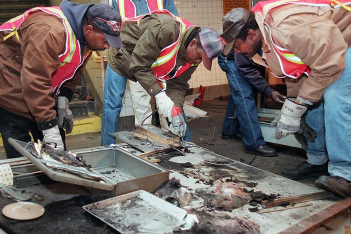 Transit workers dismantle the charred inner wall of a token booth at the Kingston Avenue and Fulton Street subway station in the Bedford-Stuyvesant section of Brooklyn, on Nov. 26, 1995, after attackers sprayed a flammable liquid into the token booth and lit it on fire, according to police.