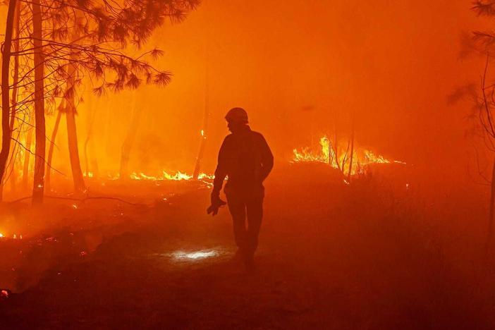 This photo provided by the fire brigade of the Gironde region (SDIS 33) shows firefighters fighting wildfire near Landiras, southwestern France, Sunday July 17, 2022.