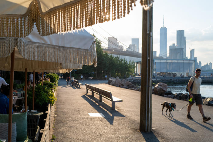 People walk along the East River in Brooklyn, New York, as temperatures reached into the 90s on Wednesday.