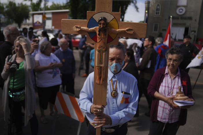 Elmer Waniandy raises the crucifix as he leads his fellow parishioner into the rededicated and newly renovated Sacred Heart Church of the First Peoples sanctuary, July 17, 2022, in Edmonton, Alberta.
