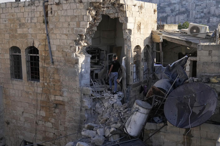 A Palestinian boy inspects the damage to a house after Palestinian gunmen were killed in an early morning Israeli military raid in the Old City of Nablus in the West Bank, Sunday, July 24, 2022.