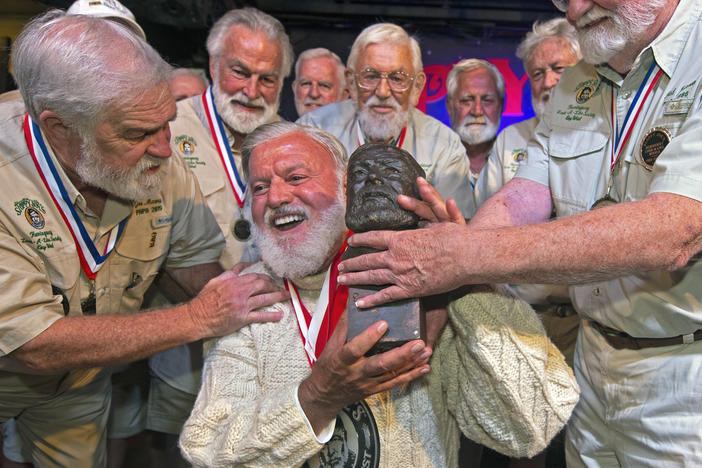 Jon Auvil, center, receives an Ernest Hemingway bust and congratulations after he won the 2022 Hemingway Look-Alike Contest at Sloppy Joe's Bar in Key West, Fla. Left of Auvil is Joe Maxey, the 2019 winner, and at right is Fred Johnson, who won in 1986. It was Auvil's eighth attempt in the annual contest.