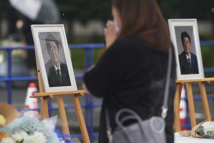 A woman prays after offering a bouquet of flowers at the memorial area set up for former Japanese Prime Minister Shinzo Abe.