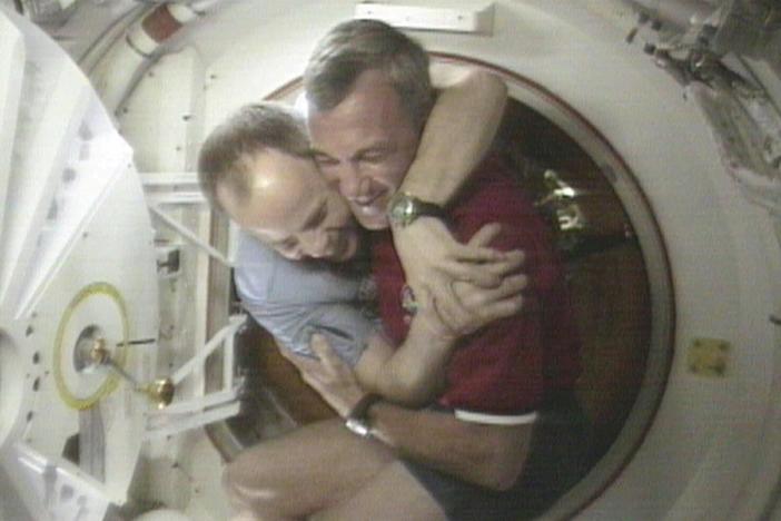 U.S. Space Shuttle Commander Terrence Wilcutt (right) and Mir Commander Anatoly Solovyev hug after opening the hatches between the space shuttle Endeavour and the Russian Space station Mir Saturday, Jan. 24, 1998, in this image from television