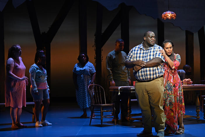 Patience (Talise Trevigne, right) comforts Castor (Reginald Smith Jr.) after his breakdown over the crush of dept and his search for a solution as other family members look on.