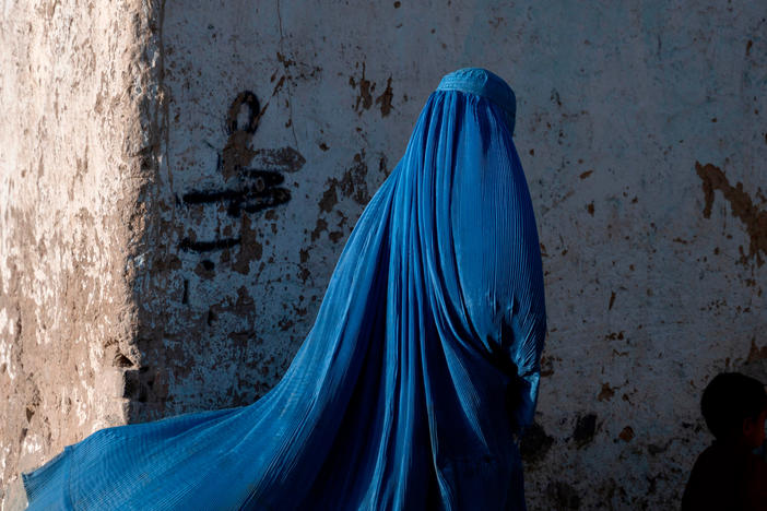 An Afghan woman walks with a child in Kabul, Afghanistan, April 28, 2022. A newly released report from Amnesty International, "Death in Slow Motion," focuses on a range of issues affecting girls and women. Foremost among them are child and forced marriage.