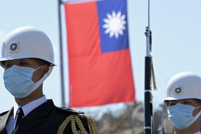 Taiwanese honor guards stand by under a national flag during a military ceremony in front of the presidential office in Taipei on March 9.